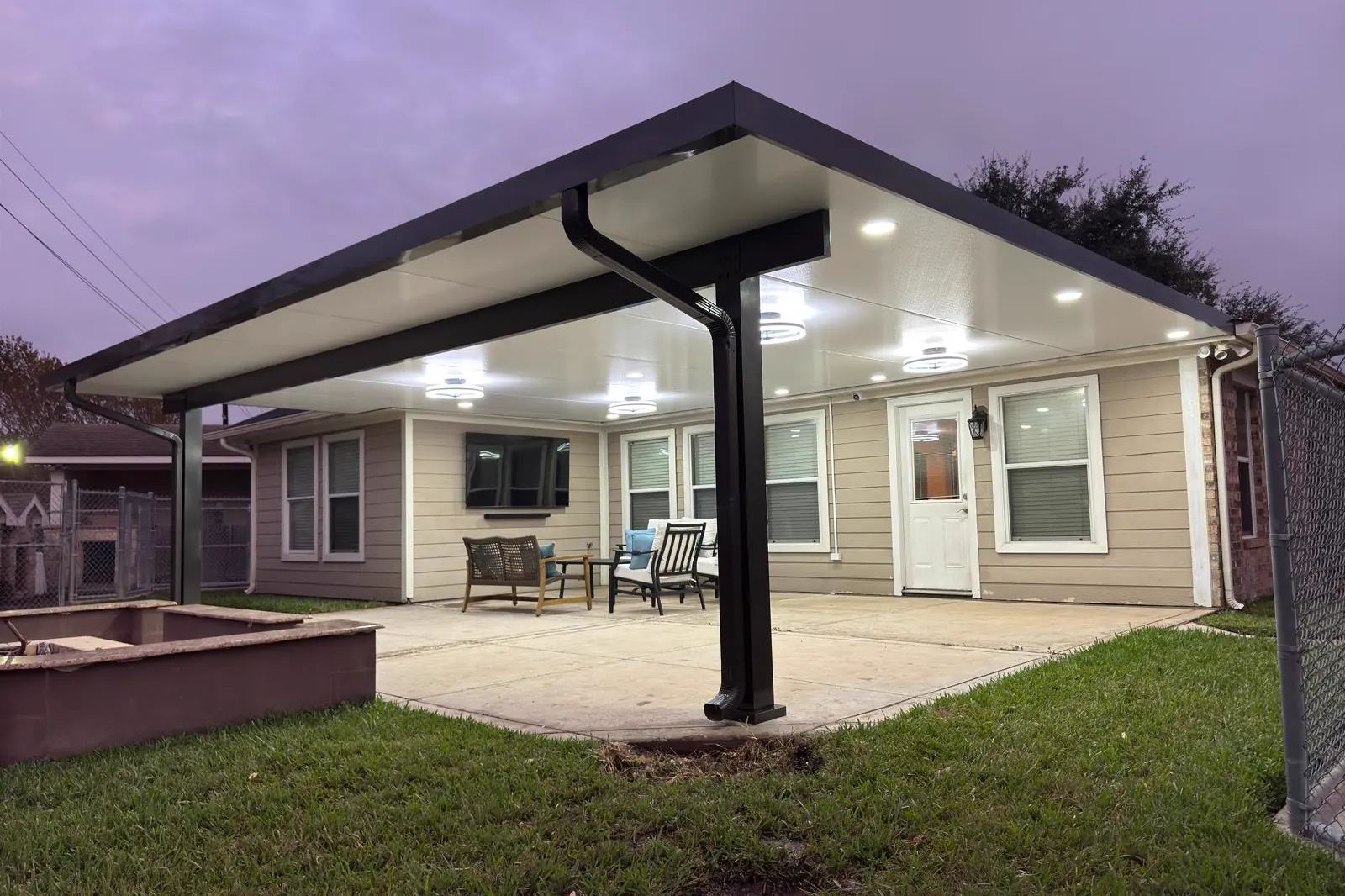 Techo de aluminio para patio con luces empotradas encendidas al anochecer.