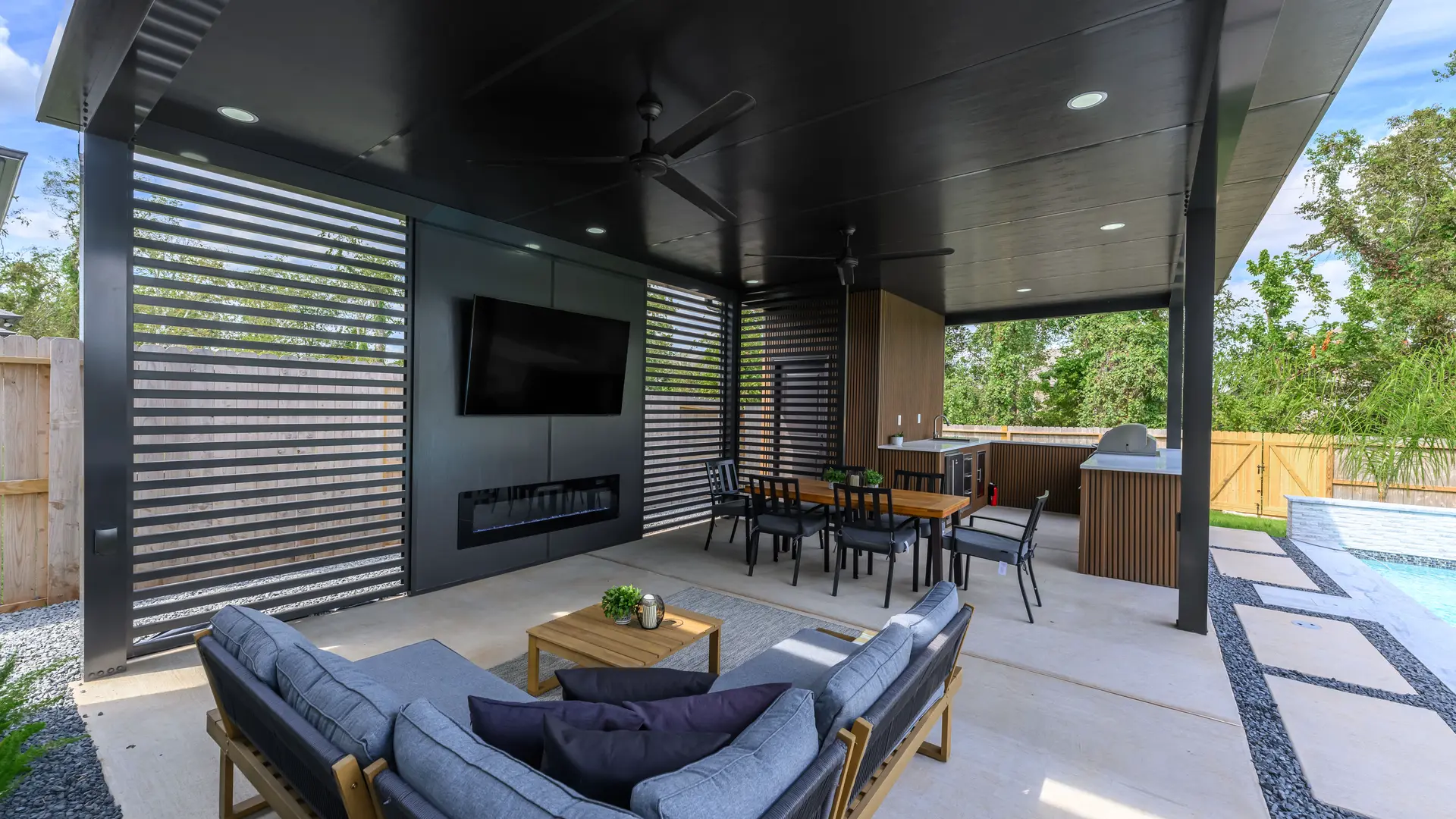 Black aluminum covered patio with a built-in fireplace, TV wall and lounge seating.