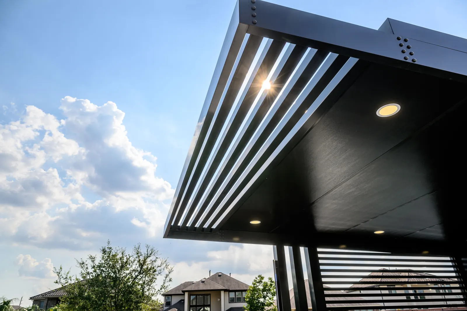 Detalle de una viga, las lamas y una luz empotrada de una pérgola de aluminio con recubrimiento en polvo.