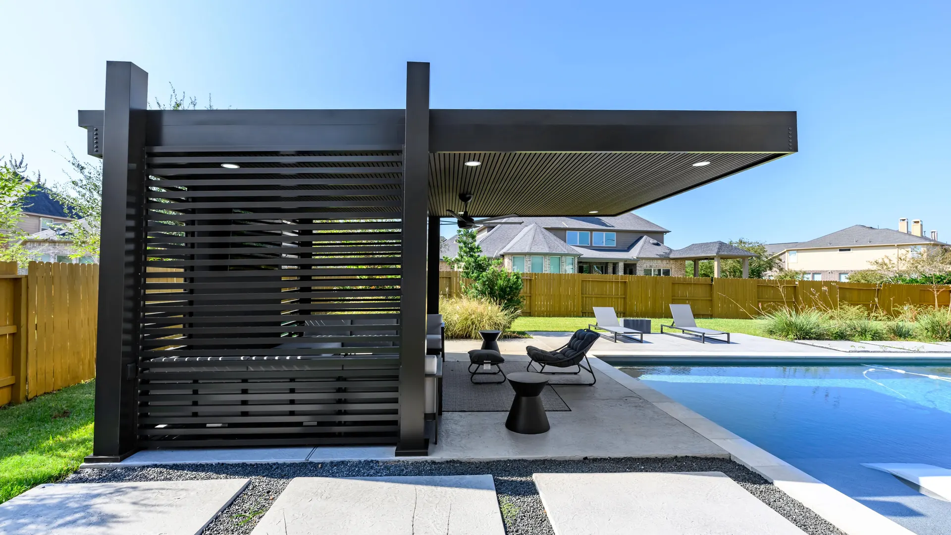 Pérgola de aluminio negro con recubrimiento en polvo y paneles de lamas junto a una piscina en un patio de Texas.